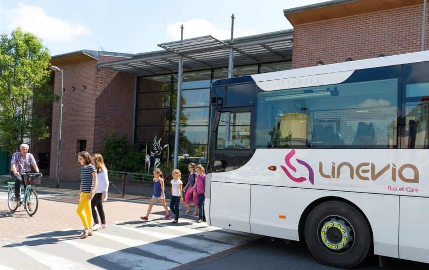 bus Linevia avec des enfants qui traversent un passage piéton et une personne âgée sur un vélo